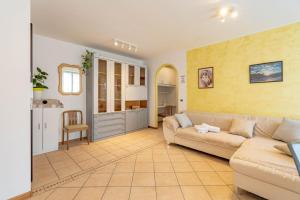 a living room with a couch and a kitchen at Casa Cataleya, Tuenno Ospitar in Tuenno