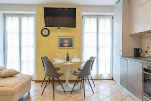 a kitchen with a table with chairs and a tv on a wall at Casa Cataleya, Tuenno Ospitar in Tuenno