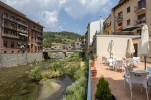 a balcony with tables and chairs next to a river at Hotel SAIOLA in Camprodon