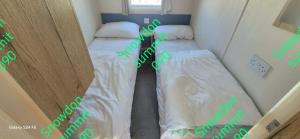 two beds in a room with green writing on them at Caravan 133 snowdon summit 090 in Barmouth