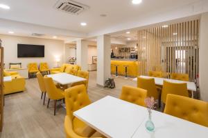 a restaurant with white tables and yellow chairs at Hotel SAIOLA in Camprodon