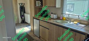 a kitchen with a counter with green writing on it at Caravan 133 snowdon summit 090 in Barmouth +6 photos