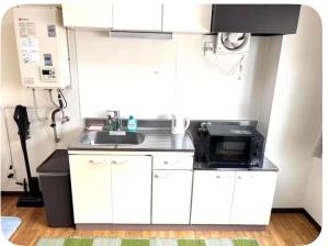 a small kitchen with a sink and a microwave at パールビル201 in Osaka