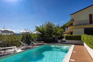 a swimming pool with chairs and umbrellas next to a house at Agriturismo La Filomena in Montefortino