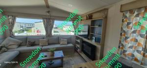 a living room with a couch and a tv at Caravan 133 snowdon summit 090 in Barmouth
