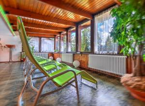a room with a bunch of green chairs and windows at Hotel Kapriol in Folgarida