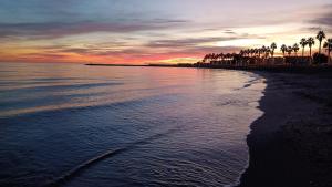 a beach with palm trees and the ocean at sunset at Chalet en Costacabana in Costacabana