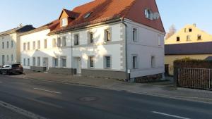 a white building with a red roof on a street at Seyfarthrooms - Großröhrsdorf 2 - zentrale Lage, stilvolle Einrichtung, Blick in den Garten in Großröhrsdorf