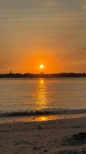 a sunset on the beach with the sun setting at Chalet de luxe in Uxelles