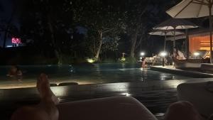 a group of people sitting around a swimming pool at night at Chalet de luxe in Uxelles