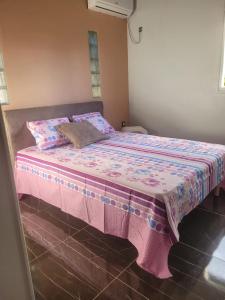 a bed in a room with a pink blanket on it at Entre terre et ciel in Baie-Mahault