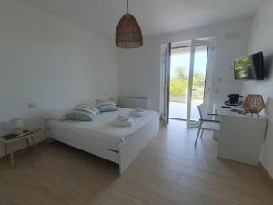 a white bedroom with a bed and a desk and a door at Suites Med Palinuro in Palinuro