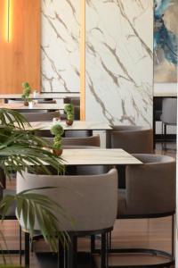 a restaurant with tables and chairs with plants at Esbjerg Hotel in Vlorë