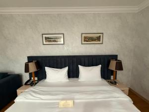 a bedroom with a large white bed with two lamps at King Hotel Astana in Astana