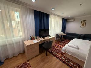 a bedroom with a bed and a desk with a television at King Hotel Astana in Astana