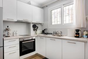 a white kitchen with white cabinets and a sink at Amarysia Residence in Athens +31 photos