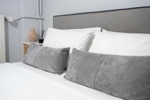 a bed with white sheets and gray pillows at Amarysia Residence in Athens