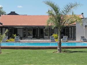 a house with a swimming pool and a palm tree at Meloding Guest House in Bela-Bela