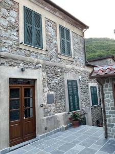 a stone building with a wooden door and green shutters at Casa Il Borgo in Tavernelle