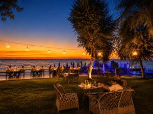 a group of people sitting at tables on the beach at night at Grand Koru Hotel Beach in Yalova