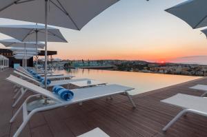 a deck with tables and umbrellas and a pool at InterContinental Malta by IHG in St. Julianʼs