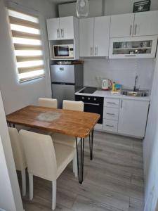 a kitchen with a wooden table and white cabinets at Kuca za odmor Toma in Ljubuški