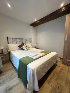 a bedroom with a bed with white sheets and green blanket at Apartamentos Rurales La Estrella in Casar de Palomero