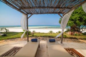 a bench under a pergola with a view of the beach at Dar Beach House - Michamvi in Michamvi