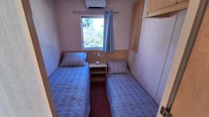 two beds in a small room with a window at Mobile-home 4, 6 places in Quédillac +1 photo
