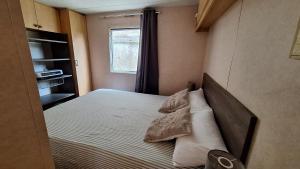 a bedroom with a bed with pillows and a window at Mobile-home 4, 6 places in Quédillac