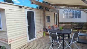 a patio with a table and chairs on a deck at Mobile-home 4, 6 places in Quédillac