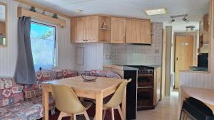 a kitchen and living room with a table and a couch at Mobile-home 4, 6 places in Quédillac