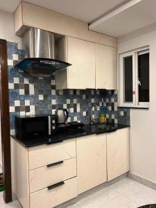 a kitchen with white cabinets and a microwave at Sky residences in Lahore