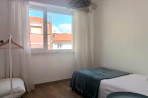 a bedroom with a window and a bed with a blue blanket at Lisbon, beach, city & surf in Trafaria
