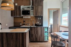 a kitchen with wooden cabinets and a table with chairs at Lisbon, beach, city & surf in Trafaria