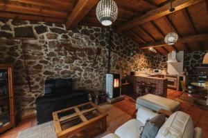 a living room with a stone wall with a fireplace at El Pajar de Tío Mariano in Tremedal