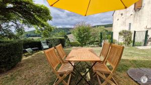 a wooden table with four chairs and a yellow umbrella at Gîte de L'Abbaye in Nolay +11 photos