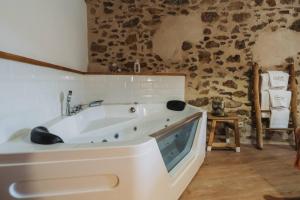 a white bath tub in a room with a stone wall at La casa del Mayoral in Tremedal