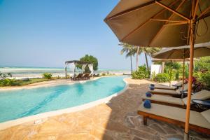 a pool with chairs and an umbrella next to the beach at Dar Beach House - Michamvi in Michamvi