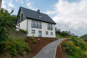 a white house with a black roof and a walkway at Eickhagen Nº7 - 10 Personen - 5 Schlafzimmer - 220qm - 4 Badezimmer - Wellness - Sauna in Olsberg