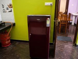 a small refrigerator in a room with a green wall at Rameswaram Homestay in Rāmeswaram
