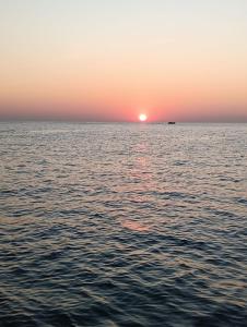 a sunset over the ocean with a boat in the distance at Avish Dubbansasi Beach stay Resort Gokarna in Gokarn