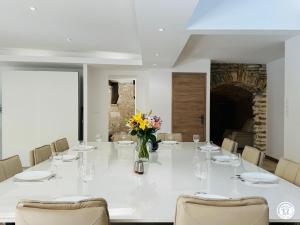 a large white table with chairs and a vase of flowers at Gîte Côté Brevon - 12 pers in Échalot