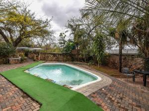 a swimming pool with green grass in a backyard at An Exclusive Guesthouse too in Nelspruit