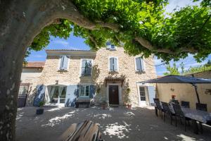 a large stone building with chairs and an umbrella at Mas de la Bimarde in Monteux