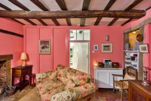 a living room with pink walls and a couch at Finest Retreats - Lavender Cottage in Methwold