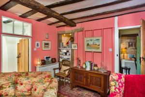 a living room with pink walls and a couch at Finest Retreats - Lavender Cottage in Methwold