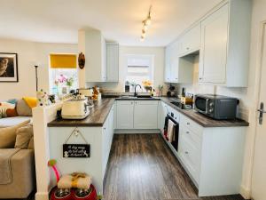 a kitchen with white cabinets and a counter top at Muddy Boots Scarpa in Kirkby Stephen +24 photos