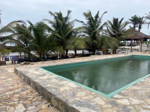a swimming pool on a beach with palm trees at Sango beach in Accra