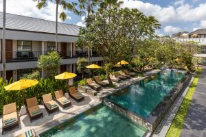 an image of a hotel pool with chairs and umbrellas at Amadea Resort & Villas Seminyak Bali in Seminyak